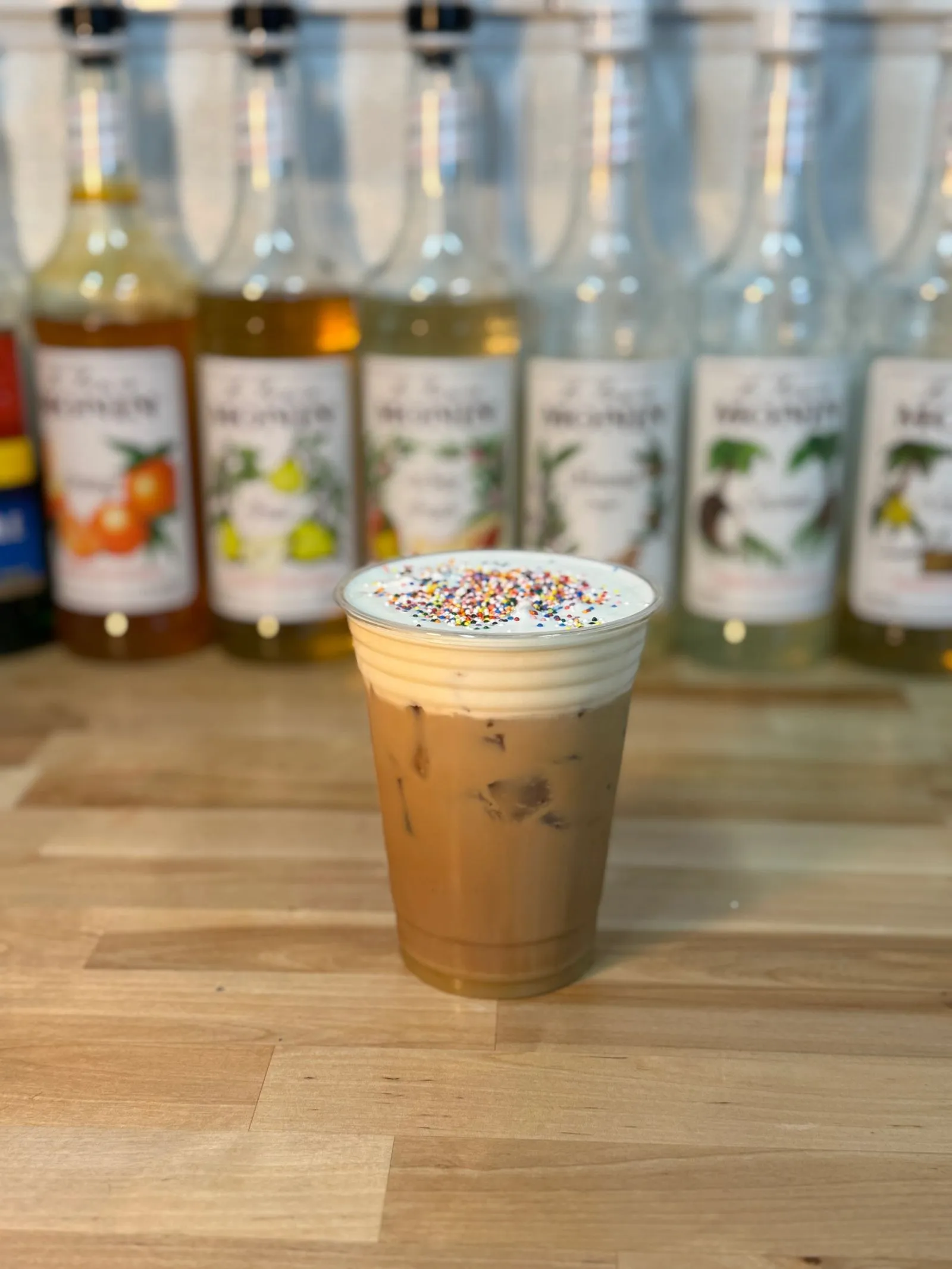 An iced latte topped with cold foam and rainbow sprinkles